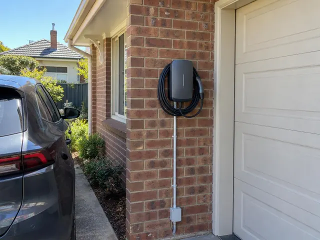 EV charger mounted on a brick exterior wall beside a garage door in Adamstown
